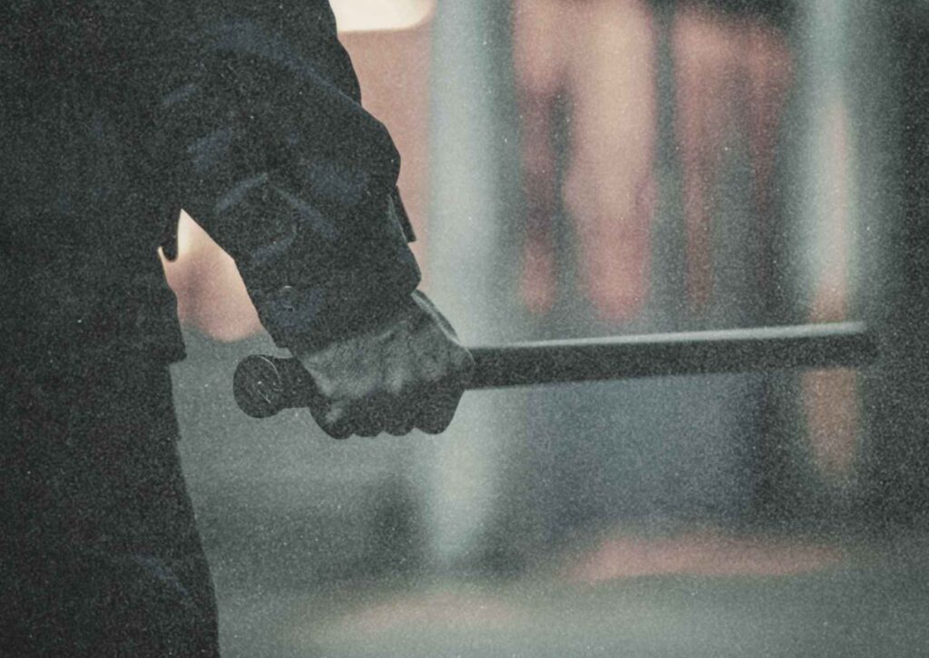 Nahaufnahme einer geballten Hand, die einen Schlagstock hält. Symbolfoto für Aggression, Wut, Bestrafung und staatliche Gewalt.