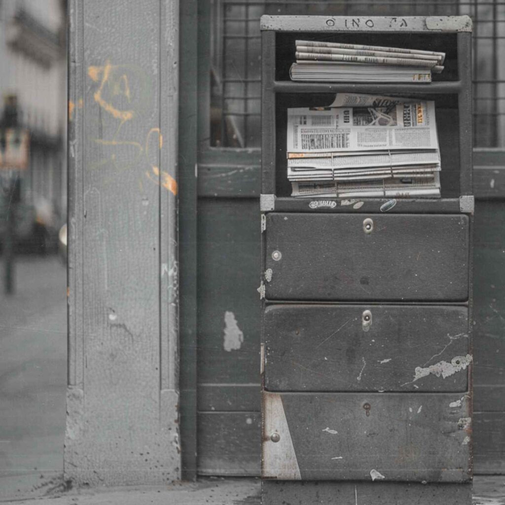 Zeitungskasten im öffentlichen Raum mit sichtbaren Zeitungen