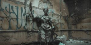 Statue der Justitia mit Waffe und Ausrüstung in verfallener Umgebung – Symbol für einen repressiven Strafstaat